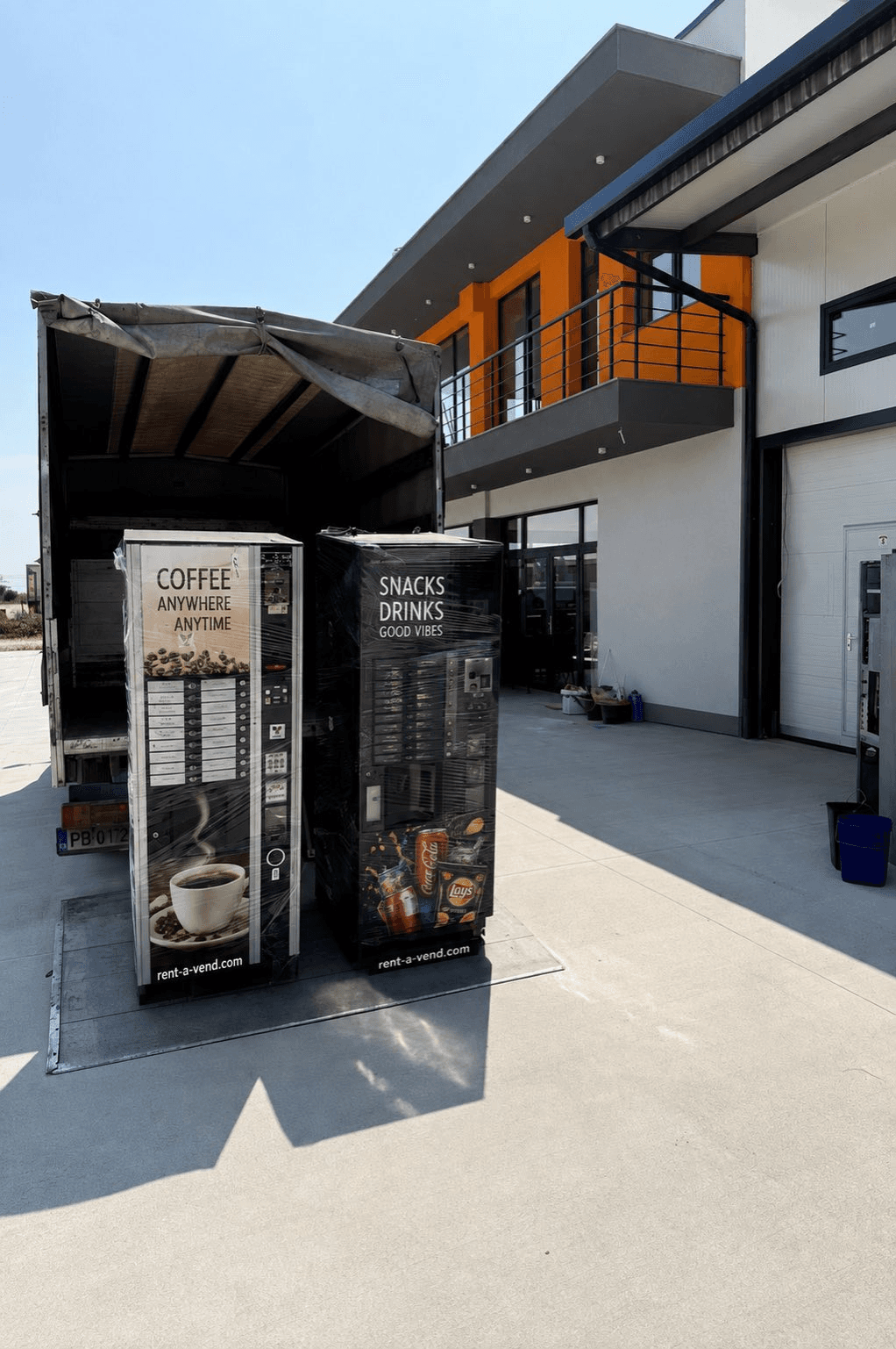 Un distributeur de café et un distributeur de snacks sur le plateau d'un camion devant l'entrepôt